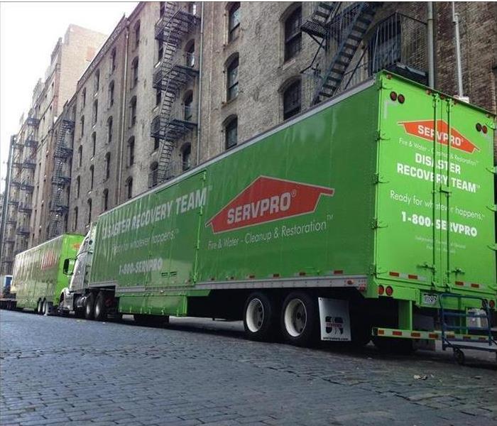 Apartment complex with two SERVPRO transport trucks parked in front 